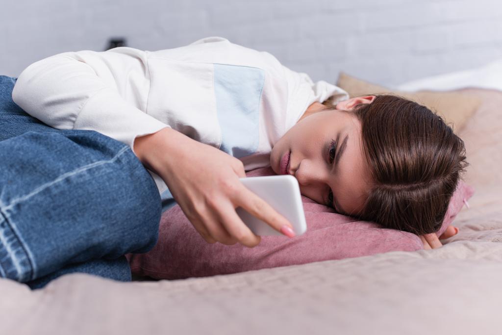 sad teenage girl using smartphone